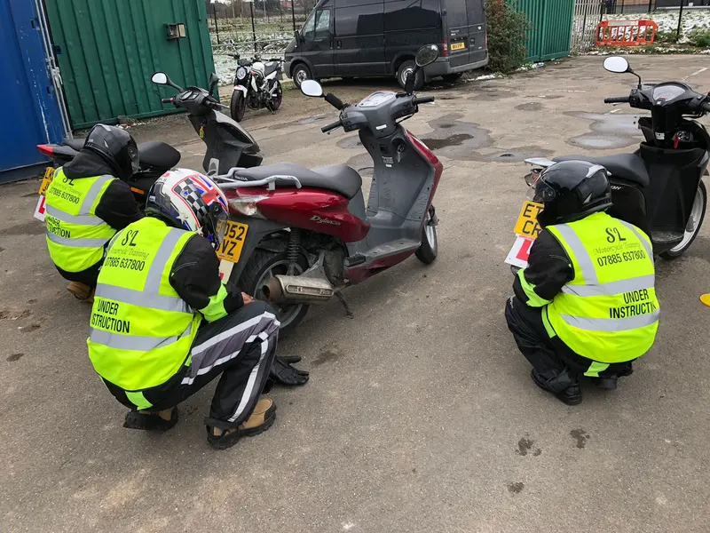 Learners in hi-vis vests doing the safety checks on scooters