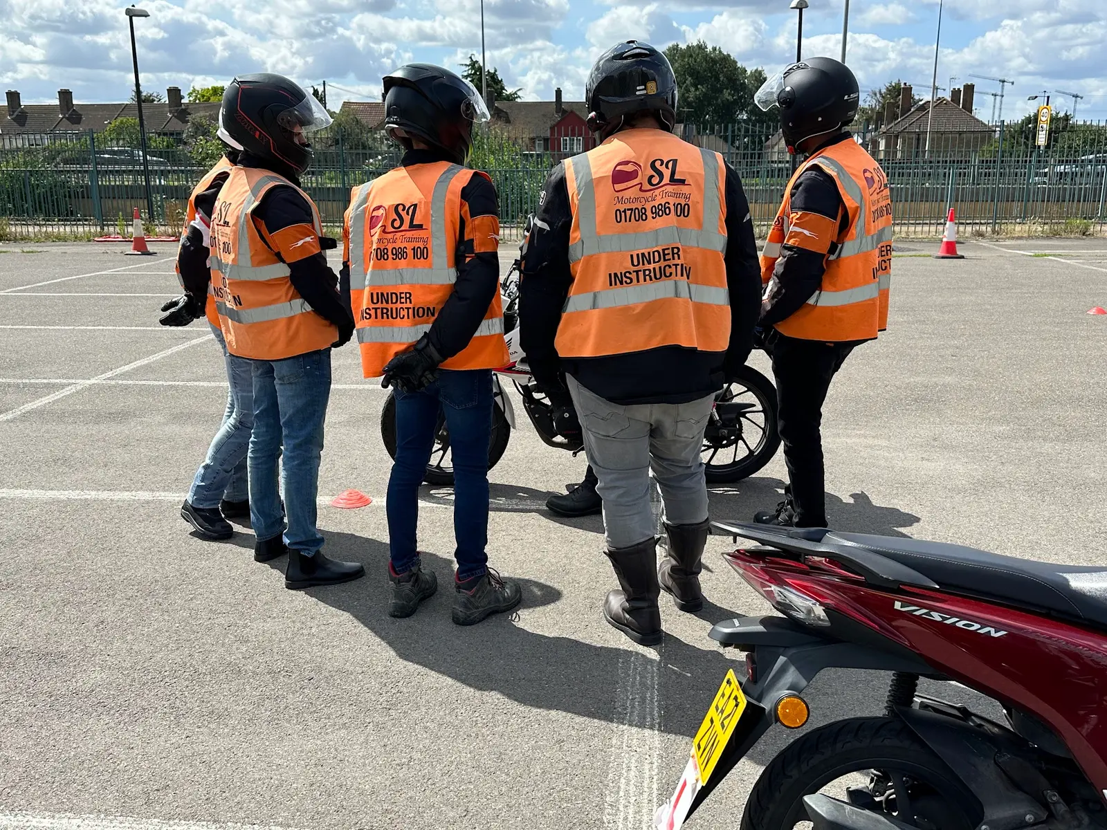 Four learners in orange SL vests listening to their instructor