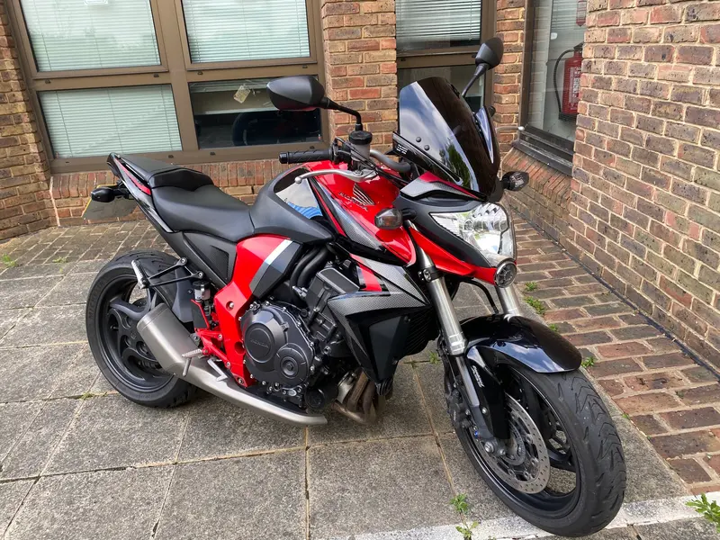A red and black motorbike parked by the building