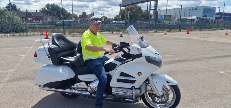 A rider in a hi-vis vest on a large white touring motorbike