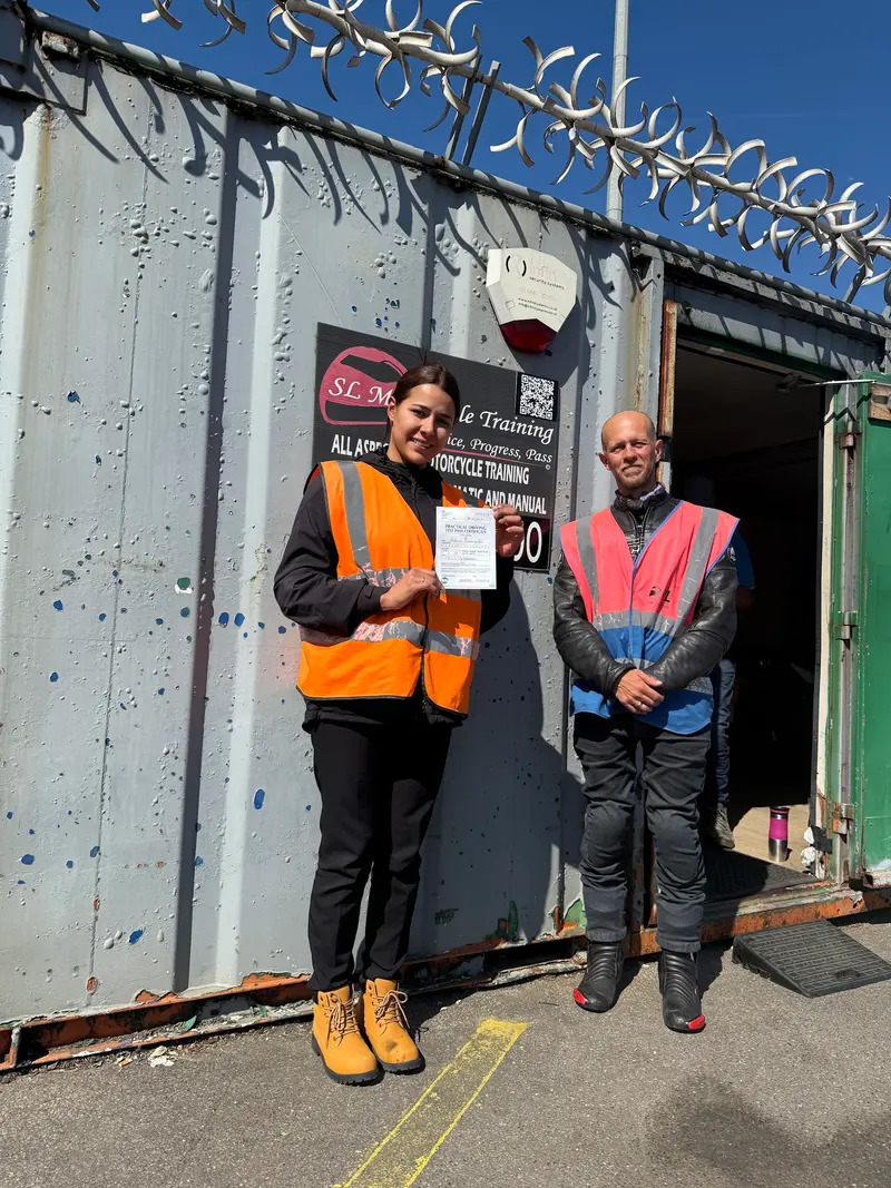 A student and instructor with a certificate in front of the SL sign