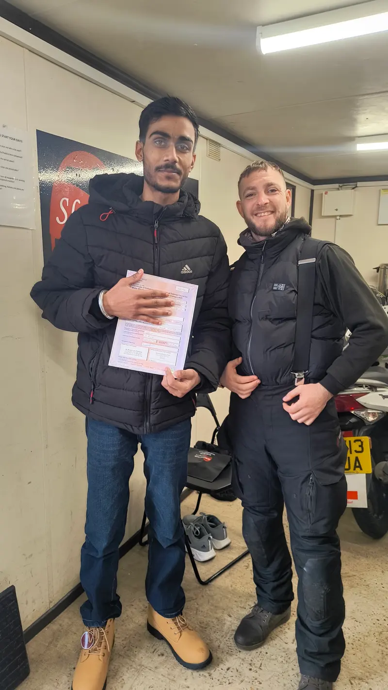 Two students holding their pass certificates